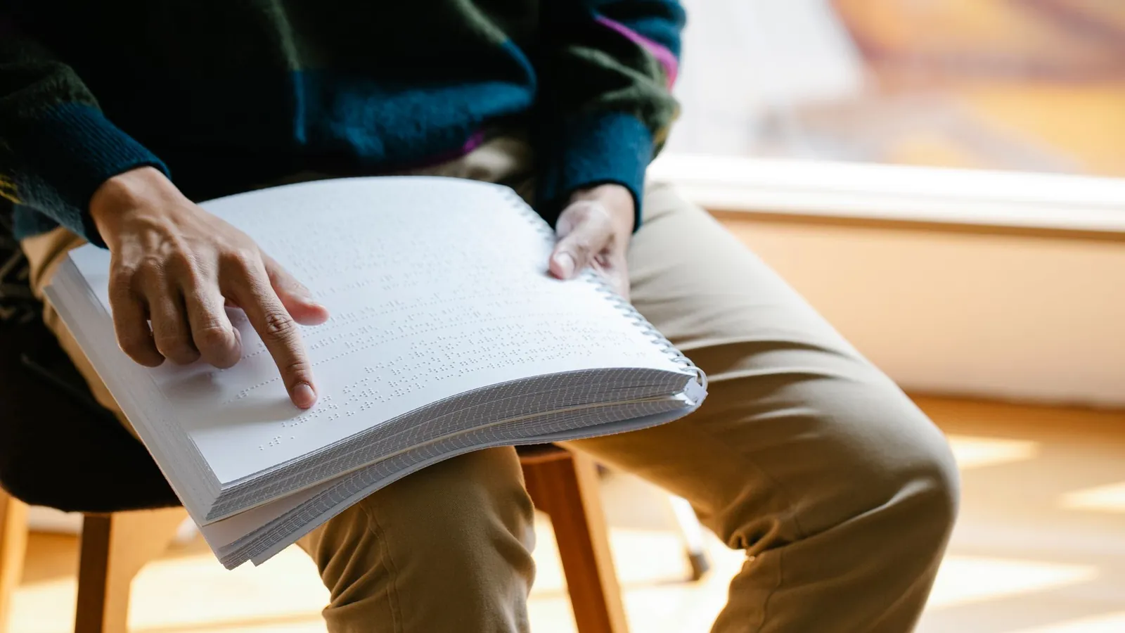 Iemand leest geconcentreerd in een dik boek, in natuurlijk licht