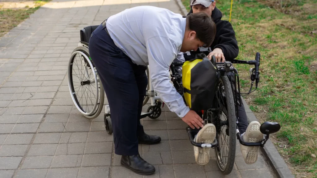 Een man helpt een andere man met zijn handbike op een buitenpad
