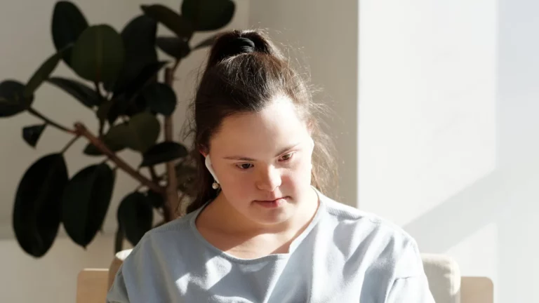 Een vrouw met het syndroom van Down werkt aan een laptop bij een plant